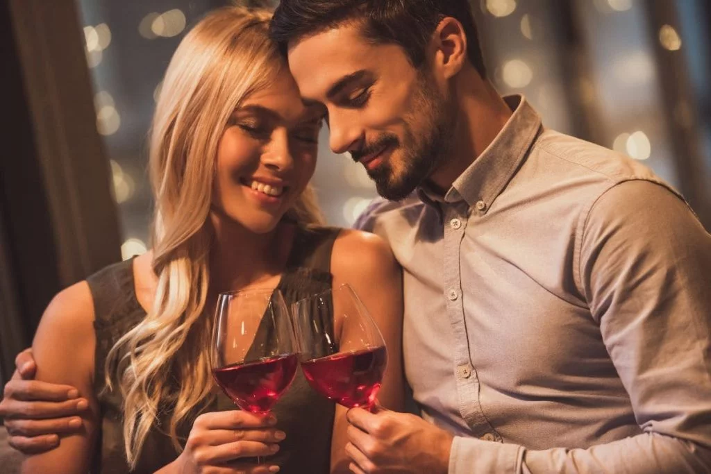 Couple on a date hugging and drinking a red drink