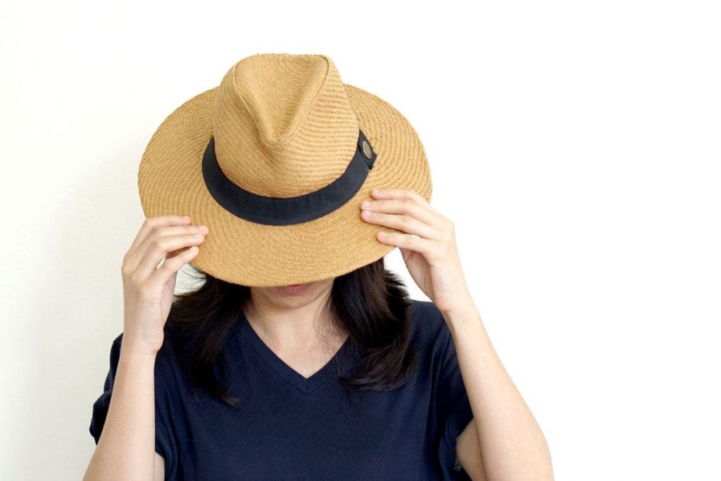 Asian woman hide face behind hat. Introvert and antisocial concept