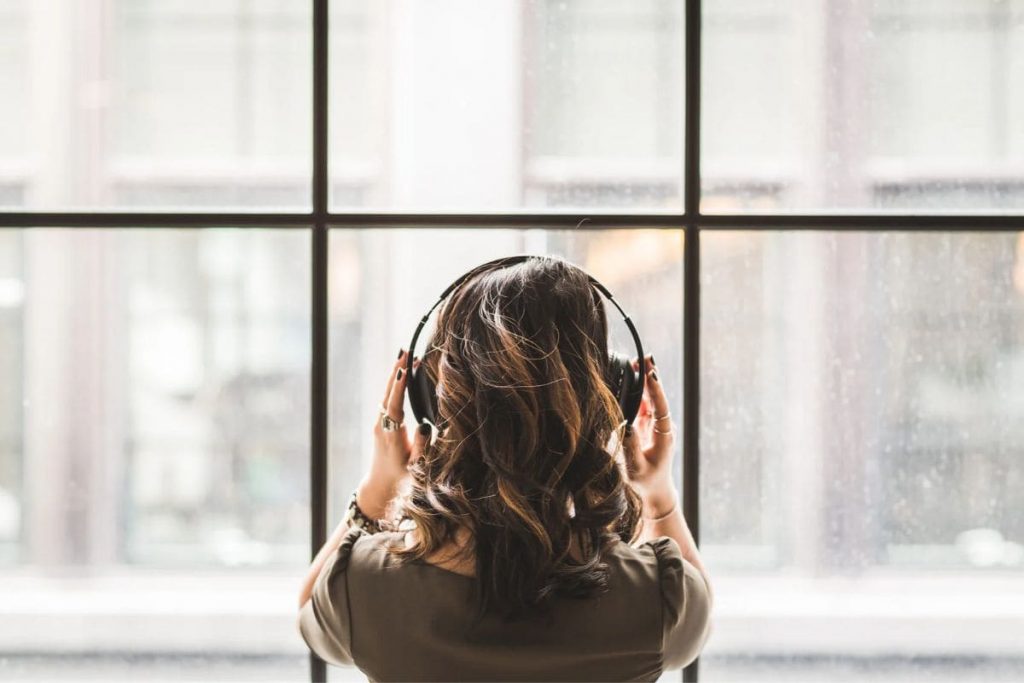 Woman listening to music on headphones and watching through a window