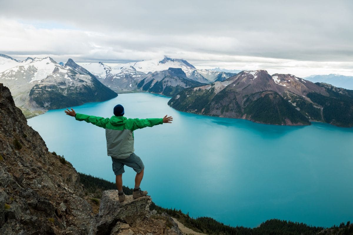 Mountain adventure. Man overlooking beautiful lake and mountains.