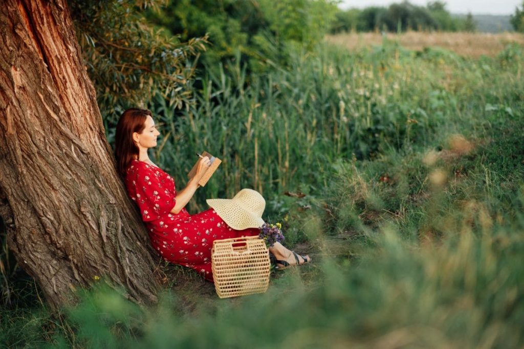 Self-care ideas list. Activities to add to self-care plan. Woman sitting under tree in a red dress