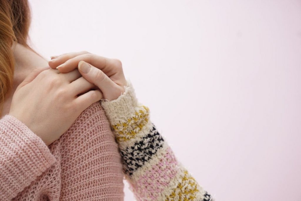 Young woman comforting her friend on pink background