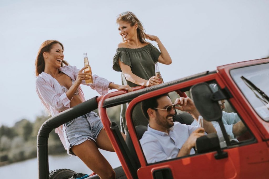 Group of young people with beer enjoying road trip