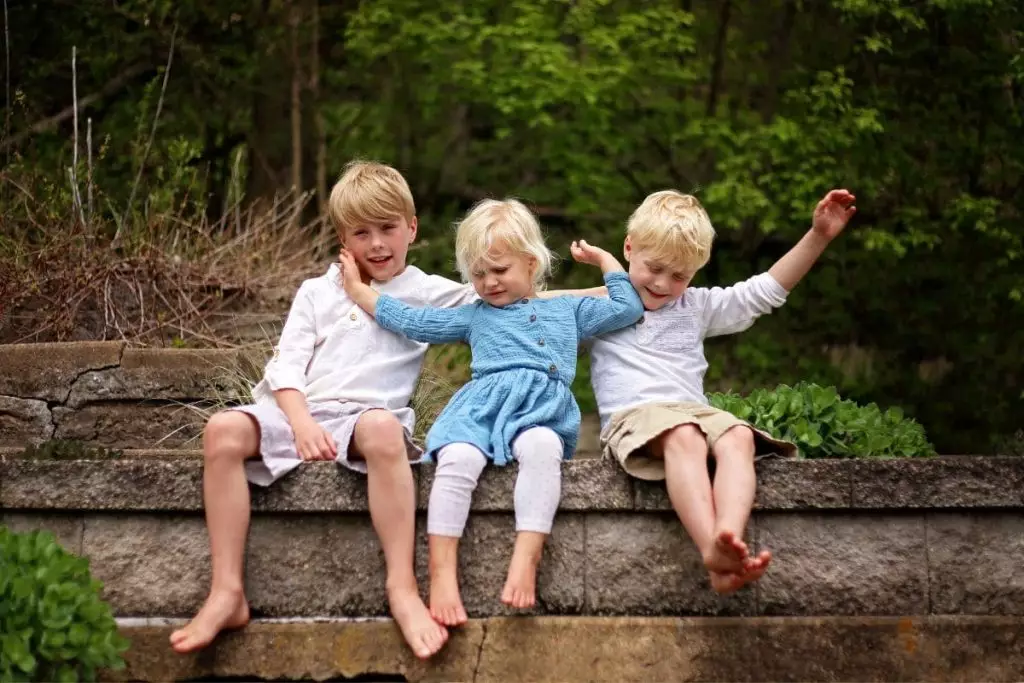 Portrait of little sister child pushing her brothers away