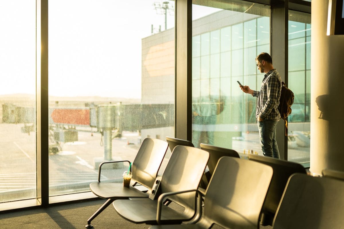 Man traveling alone, standing near a window on the airport