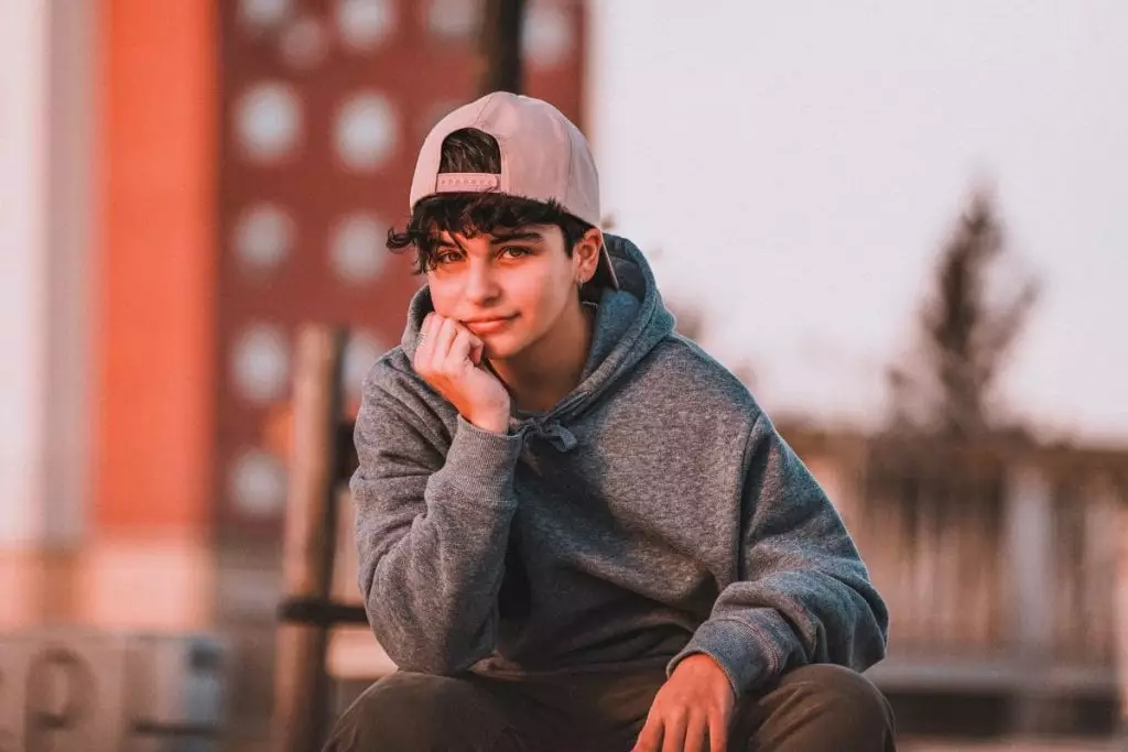Smiling trendy teenager in cap on street