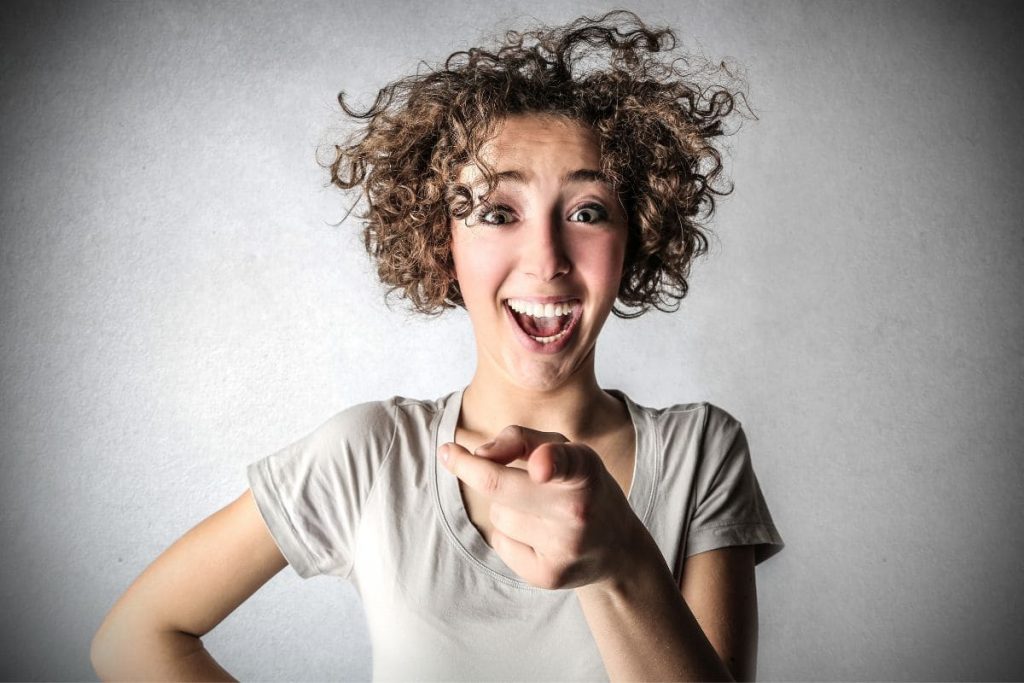 Woman with curly hair laughing at you