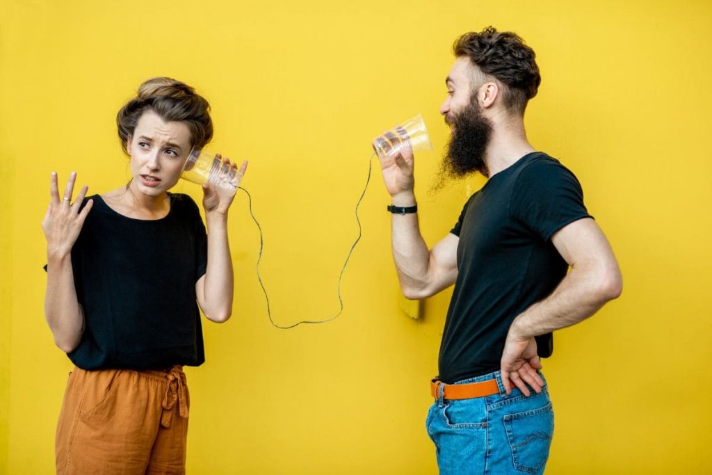 Man and woman talking with string phone on yellow background