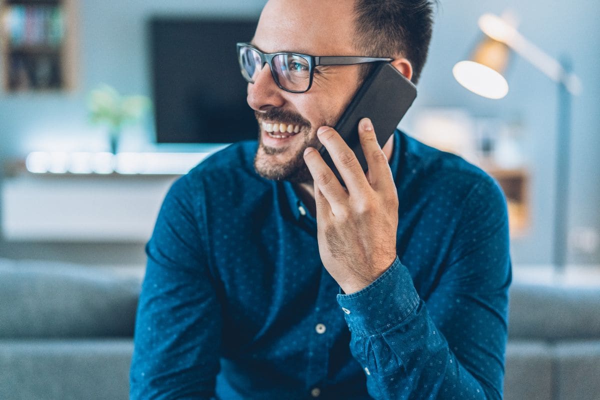 Man smiling and talking on the phone with glasses