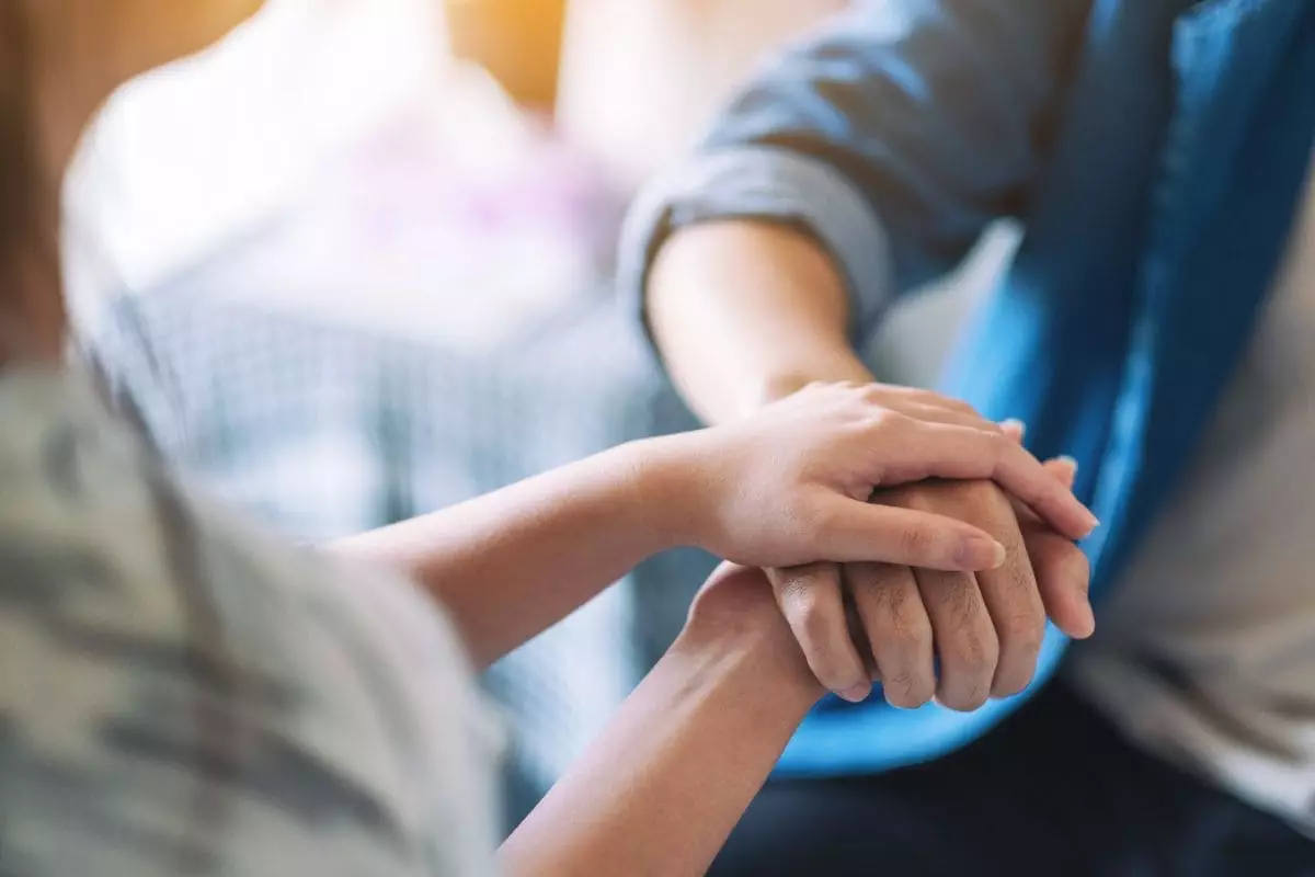 A man and a woman holding each other hands for comfort