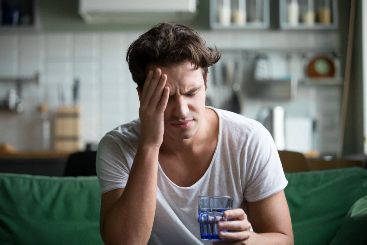 Young man suffering from headache, miraine or hangover at home
