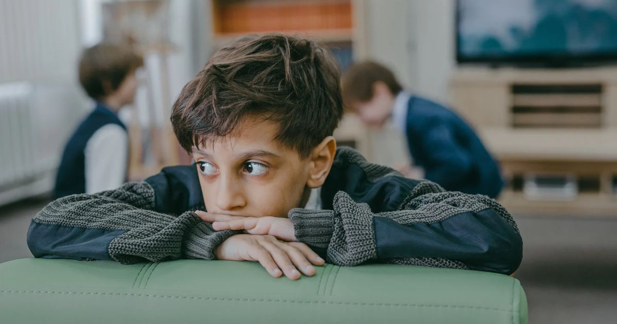 Boy in black and white long sleeve shirt sitting on green leather couch