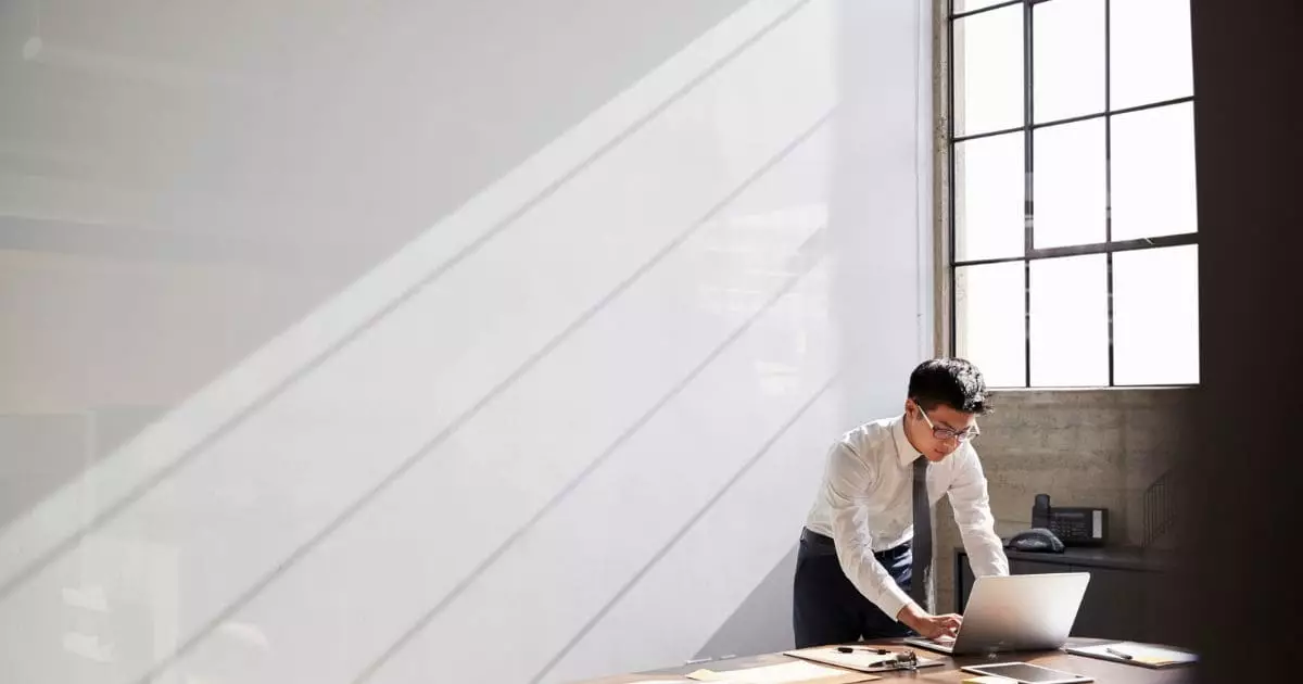 Businessman working alone using laptop in bare office